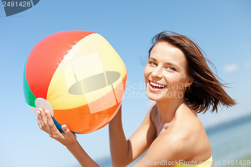 Image of girl in bikini playing ball on the beach