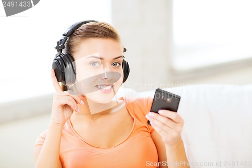 Image of woman with headphones and smartphone at home