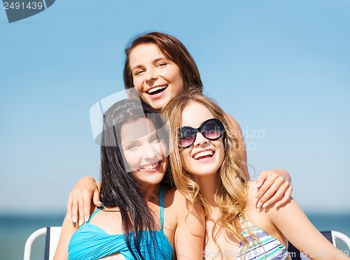 Image of girls sunbathing on the beach chairs