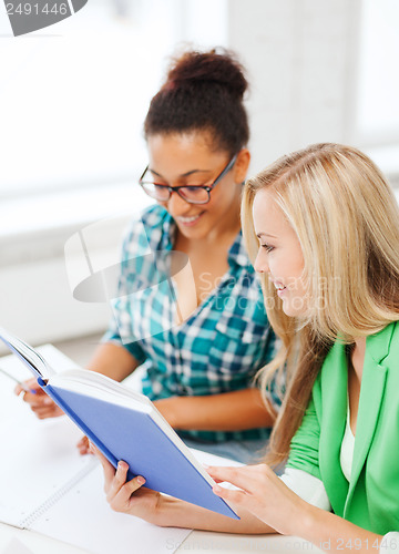 Image of smiling student girls reading book at school