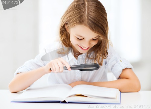 Image of girl reading book with magnifier at school