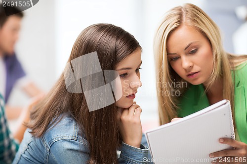 Image of student girls looking at notebook at school
