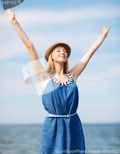 Image of girl with hands up on the beach
