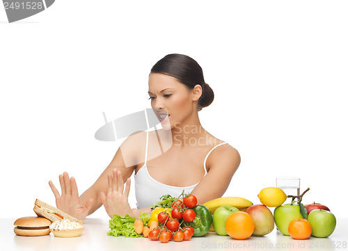 Image of woman with fruits rejecting hamburger