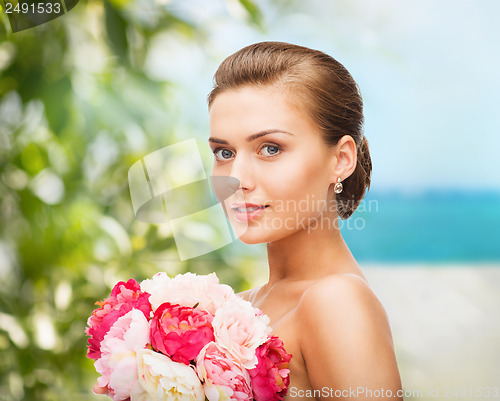 Image of woman wearing earrings and holding flowers