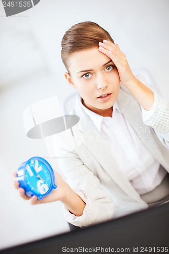 Image of stressed businesswoman holding clock