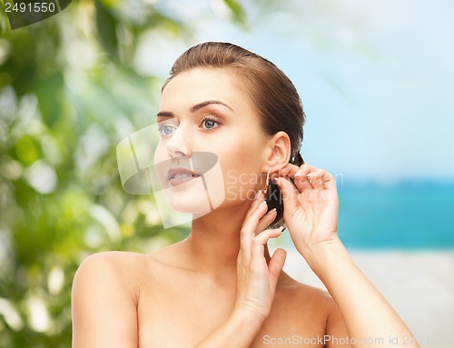 Image of beautiful woman trying on gold earrings