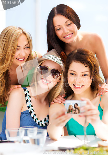 Image of girls taking photo in cafe on the beach