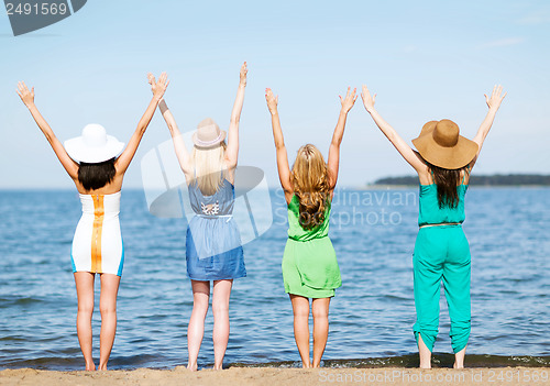 Image of girls looking at the sea with hands up