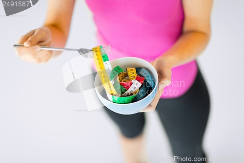 Image of woman hands holding bowl with measuring tape