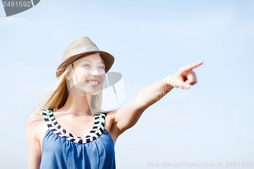 Image of girl in hat showing direction on the beach
