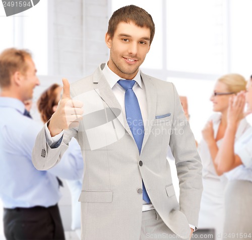 Image of businessman showing thumbs up in office