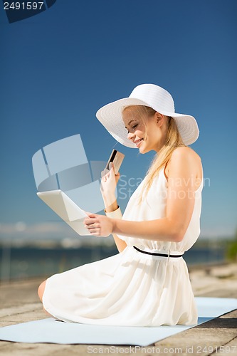 Image of woman in hat doing online shopping outdoors
