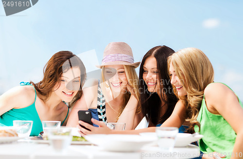 Image of girls looking at smartphone in cafe on the beach