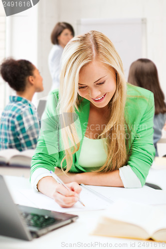 Image of student girl writing in notebook at school