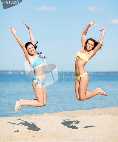 Image of girls in bikini jumping on the beach