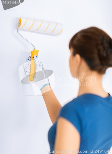 Image of woman with roller and paint colouring the wall