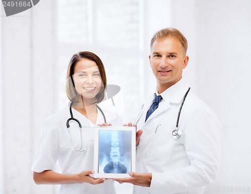 Image of two doctors showing x-ray on tablet pc