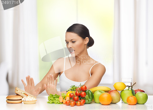 Image of woman with fruits rejecting junk food