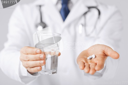 Image of doctor hands giving white pills and glass of water