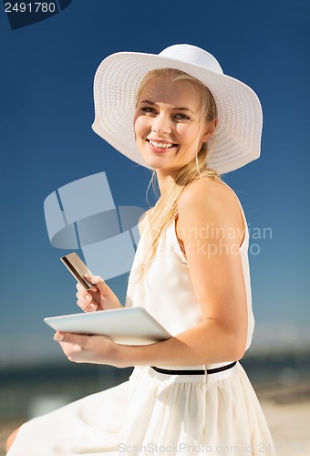 Image of woman in hat doing online shopping outdoors