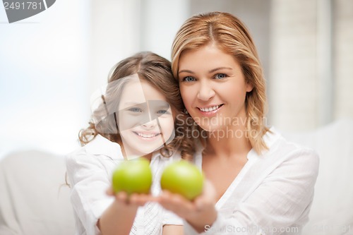 Image of mother and daughter holding green apples