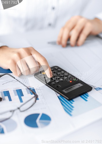 Image of woman hand with calculator and papers