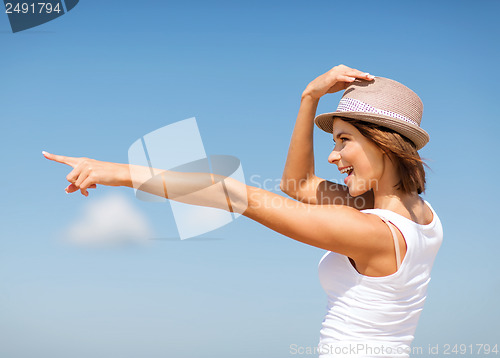 Image of girl in hat showing direction on the beach