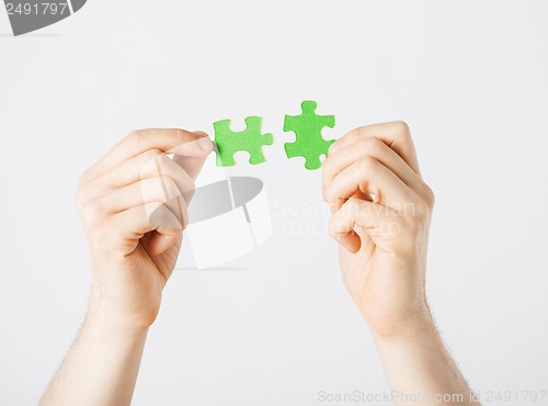 Image of two hands trying to connect puzzle pieces