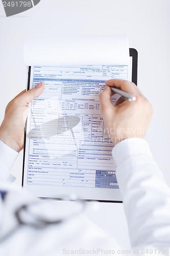 Image of male doctor holding prescription paper in hand