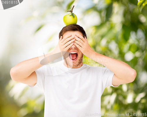 Image of man with green apple on his head