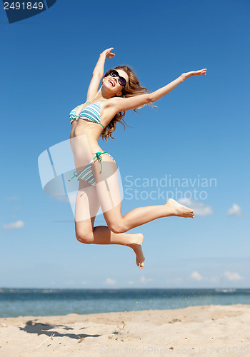 Image of woman in bikini jumping on the beach