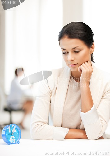 Image of businesswoman looking at alarm clock