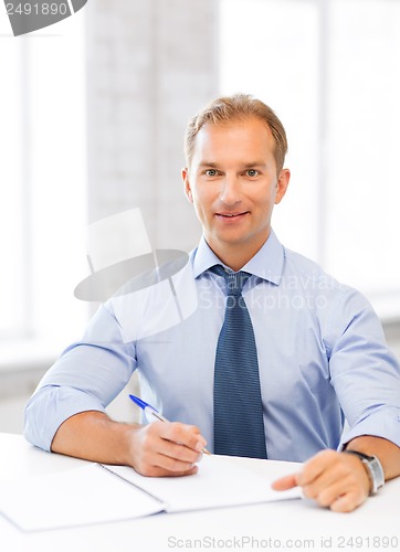 Image of handsome businessman writing in notebook