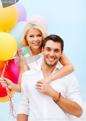 Image of couple with colorful balloons at seaside