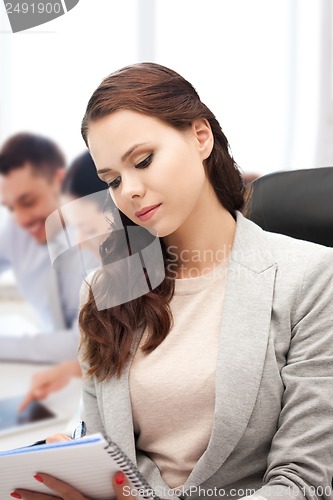 Image of attractive businesswoman taking notes in office