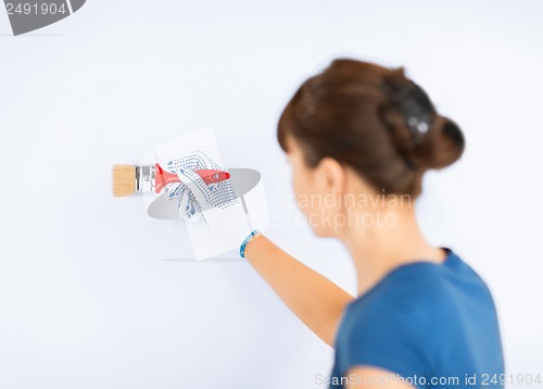 Image of woman with paintbrush colouring the wall