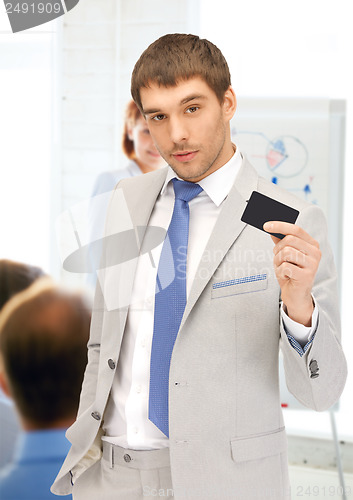 Image of businessman showing credit card in office