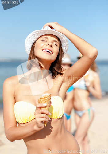 Image of girl in bikini eating ice cream on the beach
