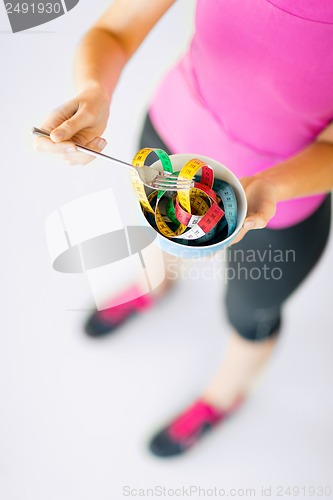 Image of woman hands holding bowl with measuring tape