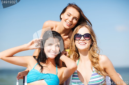 Image of girls sunbathing on the beach chairs