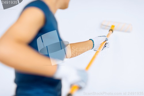 Image of woman with roller and paint colouring the wall