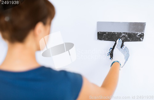 Image of woman plastering the wall with trowel