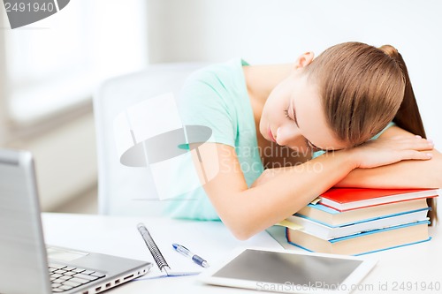 Image of tired student sleeping on stock of books