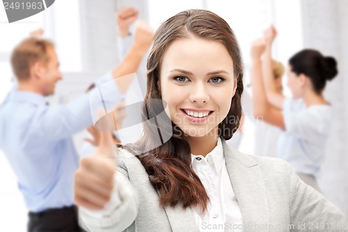 Image of businesswoman showing thumbs up in office