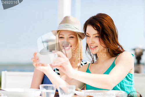 Image of girls taking photo in cafe on the beach