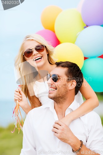 Image of couple with colorful balloons at seaside