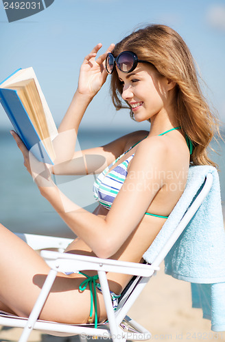 Image of girl reading book on the beach chair