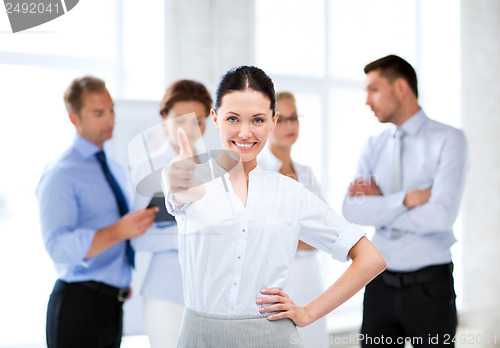 Image of businesswoman in office showing thumbs up