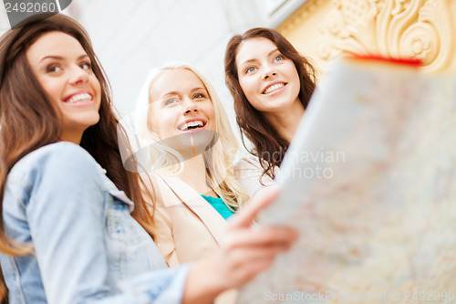 Image of beautiful girls looking into tourist map in city